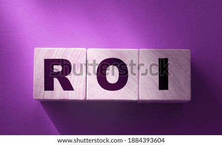 ROI - Return on Investment - letters on wooden cubes on red background. Business indicators concept.