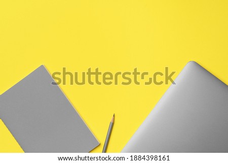 Laptop, notepad and pencil on yellow background