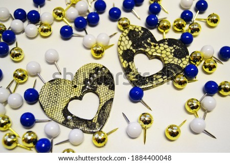 Two hearts on a white background, among colorful bright stationery buttons. Valentine's Day at the office. The big picture.
