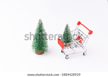 One small Christmas tree stands in a supermarket trolley, the second Christmas tree stands to the left of the trolley, isolate on a white background, used as a background or texture