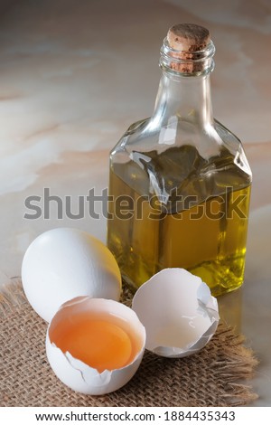 White raw eggs lie on the table next to olive oil for making mayonnaise close-up macro photography