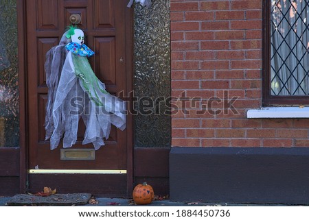 Beautiful and scary Halloween decor on typical Irish house. Halloween 2020 decoration with horror clown on the door. Painted pumpkin beside the door. Dublin, Ireland