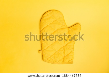 Top view of yellow oven gloves on yellow color background. Mockup for food banner and kitchen protection equipment. Royalty-Free Stock Photo #1884469759