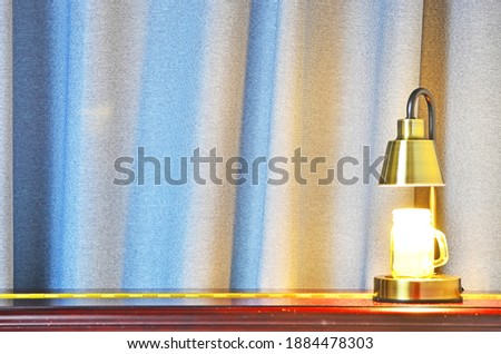 Decolative light stand on the red piano behind blue drapes