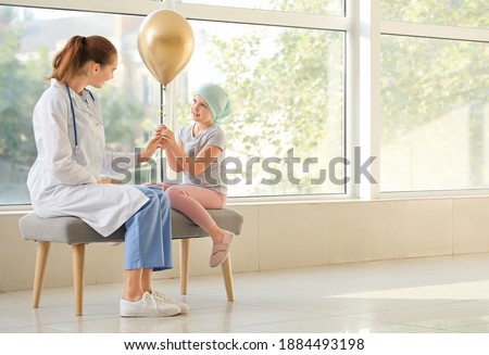 Doctor and little girl with golden balloon in clinic. Childhood cancer awareness concept Royalty-Free Stock Photo #1884493198