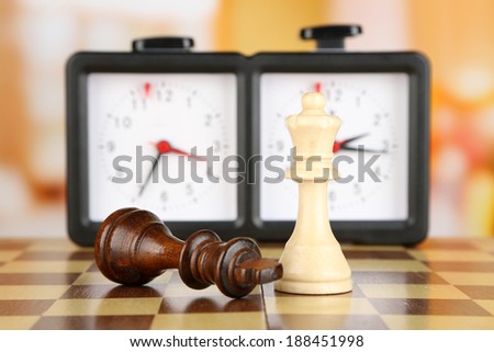 Chessboard with chess and clock on light background