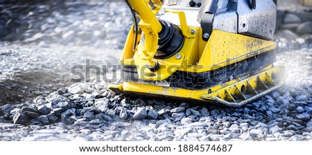 Vibratory plate heavy machine compactor for construction compacting or beating sand at sidewalk. Wide banner or panorama photo. Royalty-Free Stock Photo #1884574687