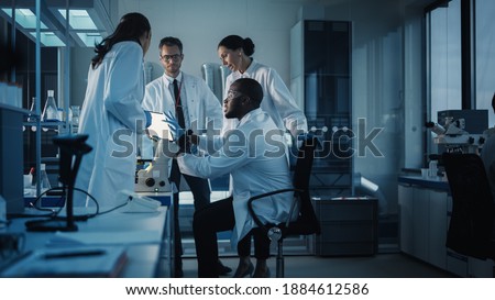 Medical Science Laboratory with Diverse Multi-Ethnic Team of Microbiology Scientists Have Meeting on Developing Drugs, Medicine, Doing Biotechnology Research. Working on Computers, Analyzing Samples