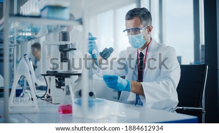 Medical Development Laboratory: Scientist Wearing Face Mask Uses Micro Pipette Dropper to Mix Petri Dish Sample. Specialists Working on Medicine, Biotechnology Research in Advanced Pharma Lab Royalty-Free Stock Photo #1884612934