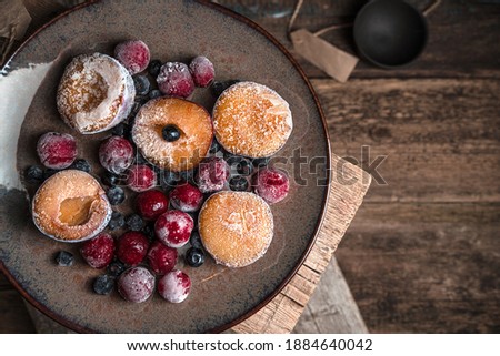 Frozen berries and plums on a brown plate. Top view with space to copy.