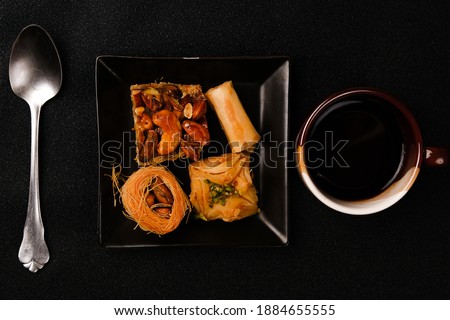 Flatlay low key picture of Arabic Baklava and cup of Arabic coffee on matte background. 