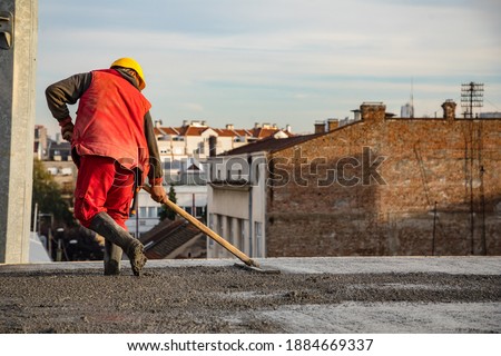 Construction worker standing on wet concrete floor. Standing and ready for wet cement transfer from truck to steel grid bar on the ground.
