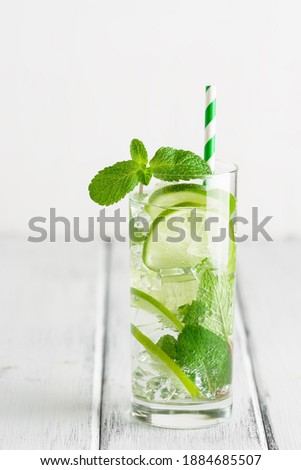 Refreshing mojito cocktail with lime and mint on a white rustic wooden table