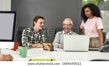 Aged man, senior intern looking happy while using laptop and showing results to his young colleagues, Friendly workers mentoring and training new employee, monitoring his progress at work, Web Banner