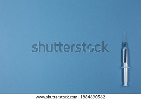 Syringe with vaccine on blue background