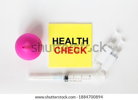Yellow sticker with text Health Check on a white background with syringes, enema and ampoule. Medical concept photo