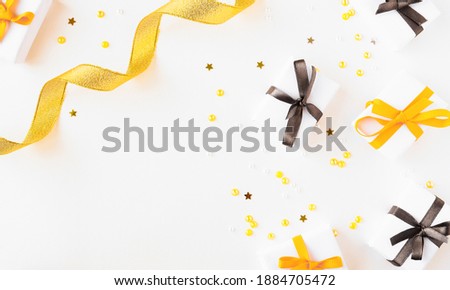 Several gifts with bright ribbons lie on a light background with a copy space. Gold ribbon and confetti in trendy colors.