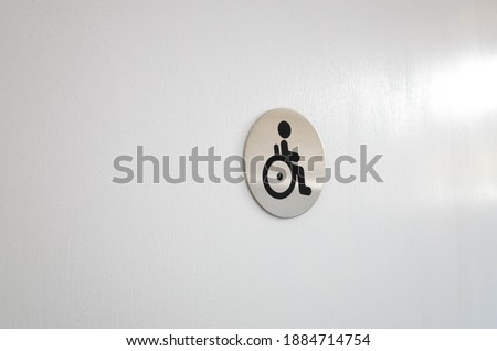 The disabled sign or wheelchair user and handicap on a white door or wall. Concept of accessible public facilities. Copy space for text.