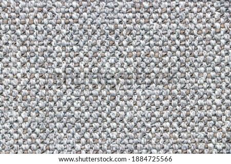 Sample of a gray fabric with a pronounced weave of threads. Textiles and wool. Blank background and close-up.