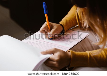 Latin woman hands writing and signing a document or a questionnaire in South America