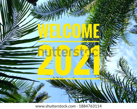 Selective focus.Text WELCOME 2021 with blue sky and green tree background.