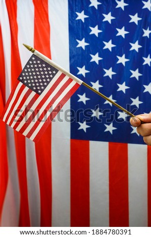 small American flag with stars and stripes hold with hands against US flas. 4th july. independence day. 