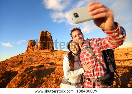 Selfie - Happy couple taking self portrait photo hiking. Two friends or lovers on hike smiling at camera outdoors mountains by Roque Nublo, Gran Canaria, Canary Islands, Spain.