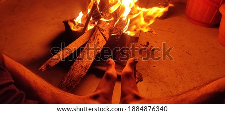uttarakhand,india-3 may 2020:this is a picture of fire and a foot in winters. A man is near fire and feeling its warmness.