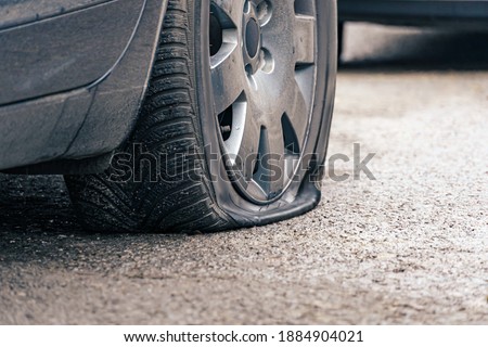 flat car tire close up, punctured wheel Royalty-Free Stock Photo #1884904021