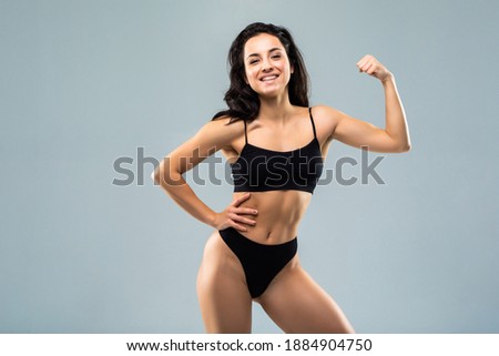 sport fitness woman flexing show her biceps muscles, young smile girl athletic body, perfect figure wear black panties over white background