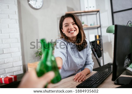 Beautiful businesswoman laughing and cheering with beers. Happy woman celebrate in the office.