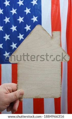 male hand holding sign of wooden  house on background of United States of America