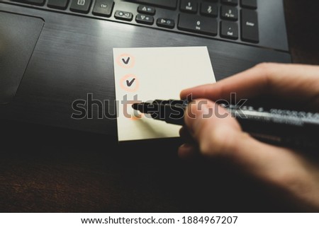 Check boxes on white paper plans. hand with black marker makes marks in the check list