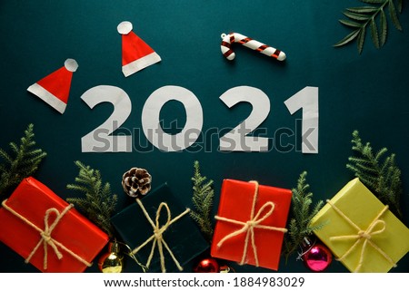 Happy New Year 2021. white digits 2021 with christmas hat are on dark background with glitter. Holiday Party Decoration or postcard concept with top view and copy space