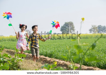Rural kids playing in  agricultural field with windmill Royalty-Free Stock Photo #1884986305