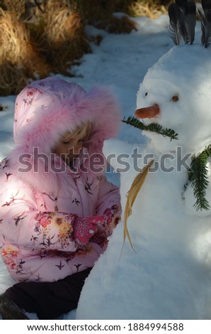 Little blonde girl in the snowy mountains.