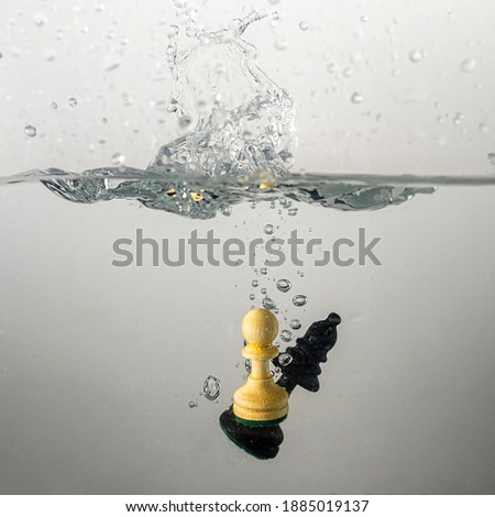 Some chess pieces drop with a splash in clear water