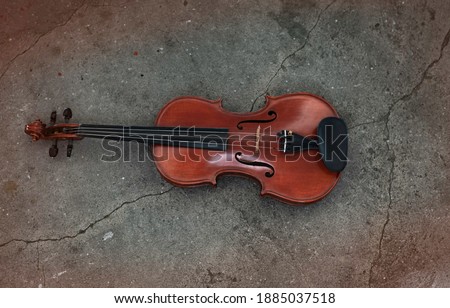 Top view of violin put on grunge surface cement ground floor,show detail of acoustic instrument,blurry light around