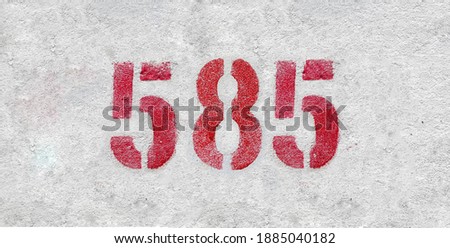 Red Number 585 on the white wall. Spray paint.