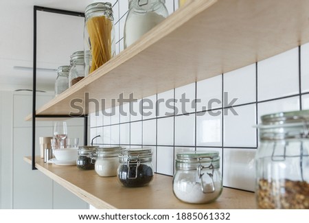 Custom made plywood shelves on a white tiled kitchen wall. 