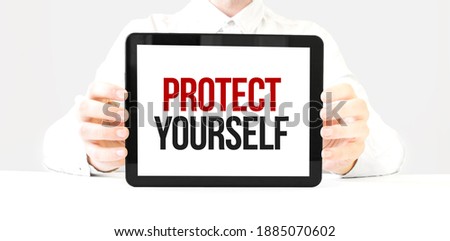 Text PROTECT YOURSELF on tablet display in businessman hands on the white bakcground. Business concept
