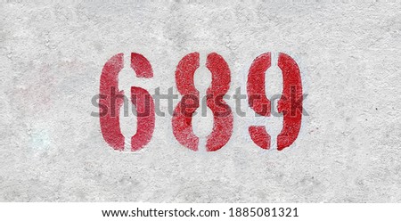 Red Number 689 on the white wall. Spray paint.