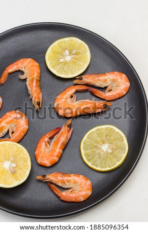 Shrimp and lemon wedges on black plate.  White Background. Flat lay. 