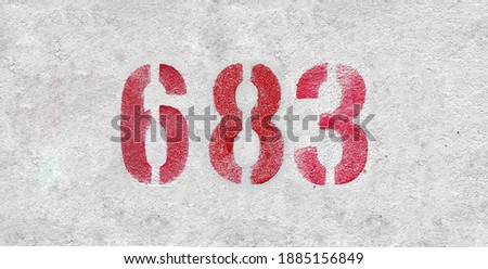 Red Number 683 on the white wall. Spray paint.