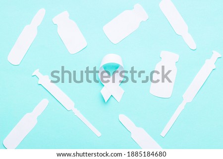 oncology and disease symbol and medical supplies such as vial, syringe made white paper on blue background. above view. medication concept.