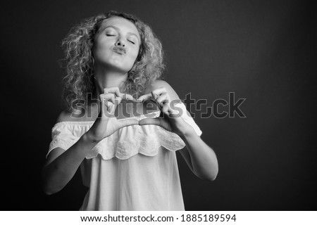 Young beautiful woman with blond curly hair against gray background