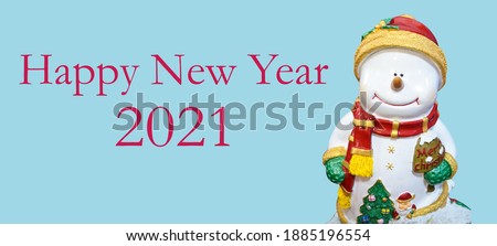 Smile snowman in snow wearing red hat and scarf.Smile snowman in snow wearing  green glove.snowman doll with"merry chrismas" word on blue background with "HAPPY NEW YEAR 2021"word and clipping path.