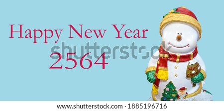 Smile snowman in snow wearing red hat and scarf.Smile snowman in snow wearing  green glove.snowman doll with"merry chrismas" word on blue background with "HAPPY NEW YEAR 2564"word and clipping path.
