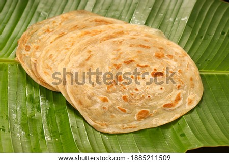 Homemade kerala Porotta or paratha,layered flat bread made using maida or all purpose wheat flour arranged in a fresh green banana leaf. Royalty-Free Stock Photo #1885211509