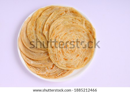 Homemade kerala Porotta or paratha,layered flat bread made using maida or all purpose wheat flour arranged in a white ceramic plate with white background. Royalty-Free Stock Photo #1885212466